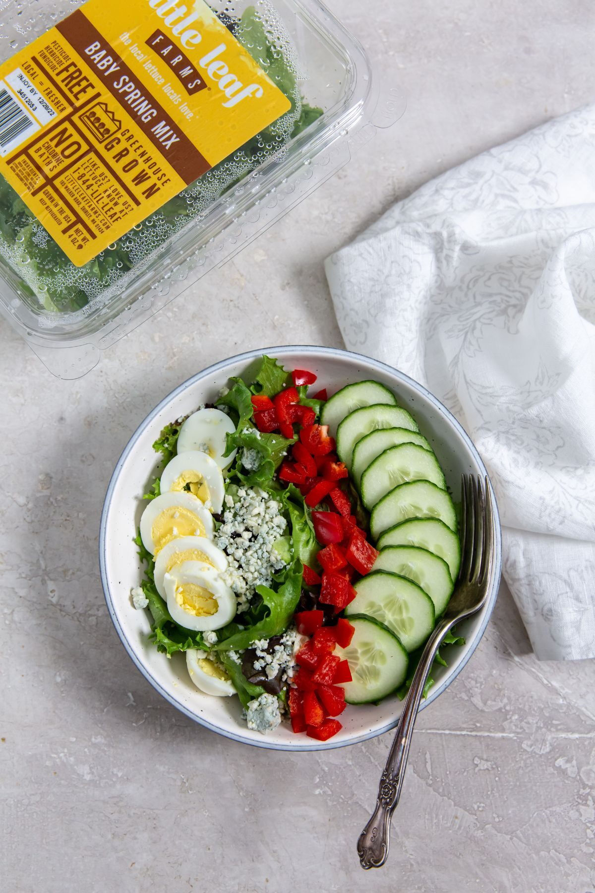 a salad with egg, cheese, peppers and cucumbers and a white napkin