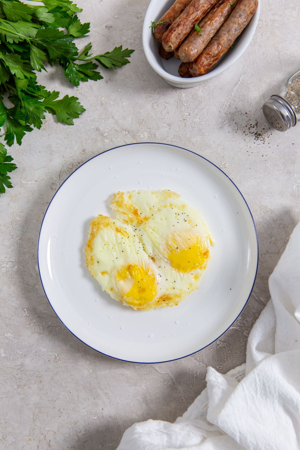 Air Fryer fried eggs on a white plate with a side breakfast sausage