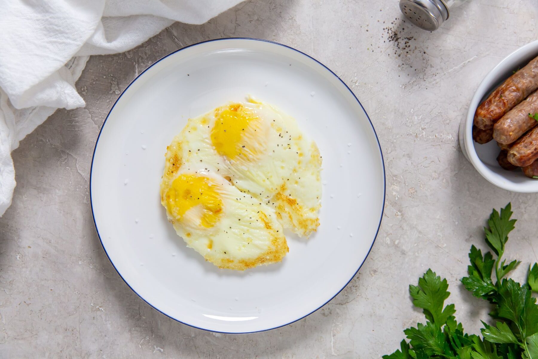 Air Fryer fried eggs on a white plate with a side breakfast sausage