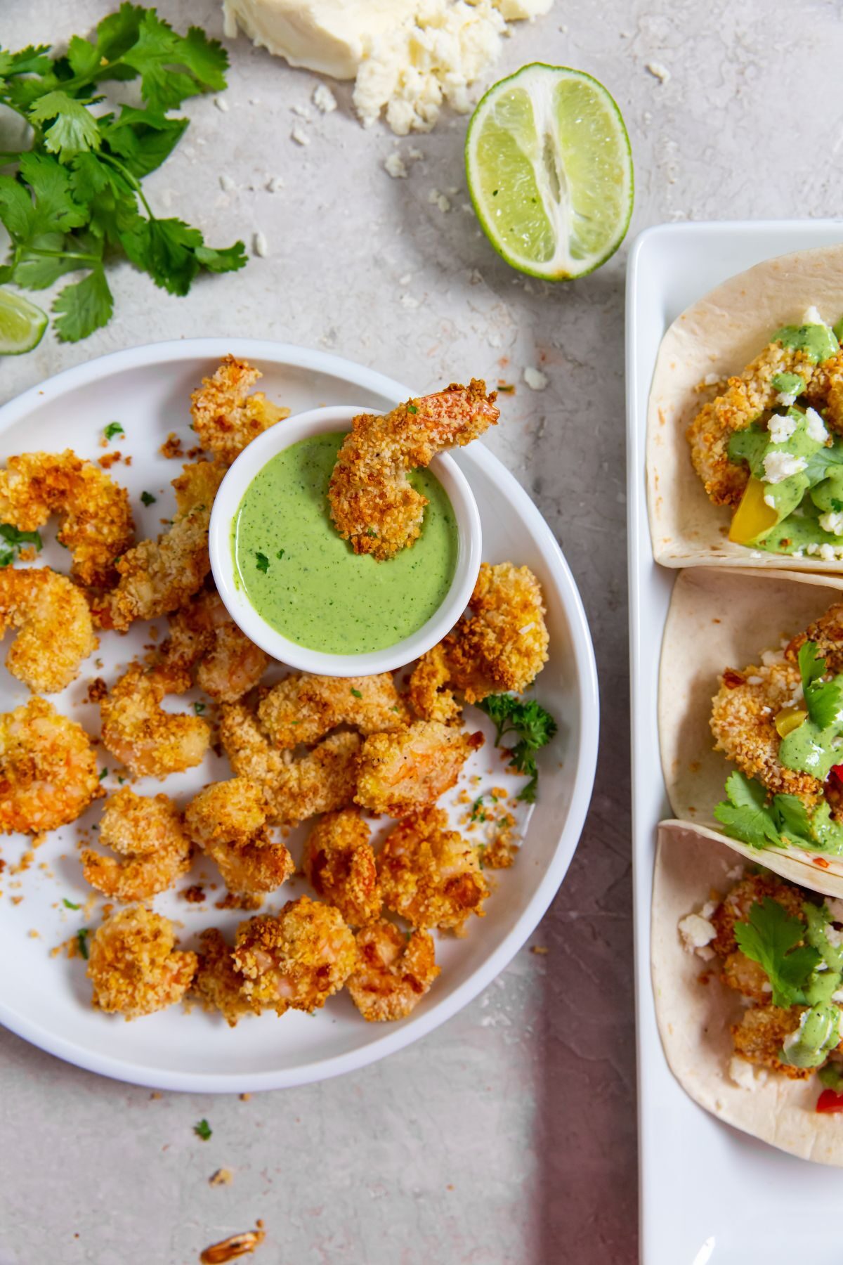 air fried panko shrimp on white plate with dipping sauce next to a plate of three shrimp tacos