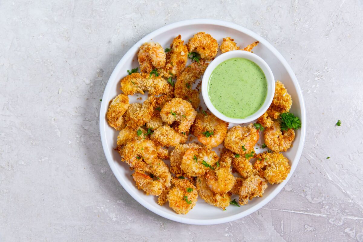 air fryer panko shrimp on white plate with green dipping sauce