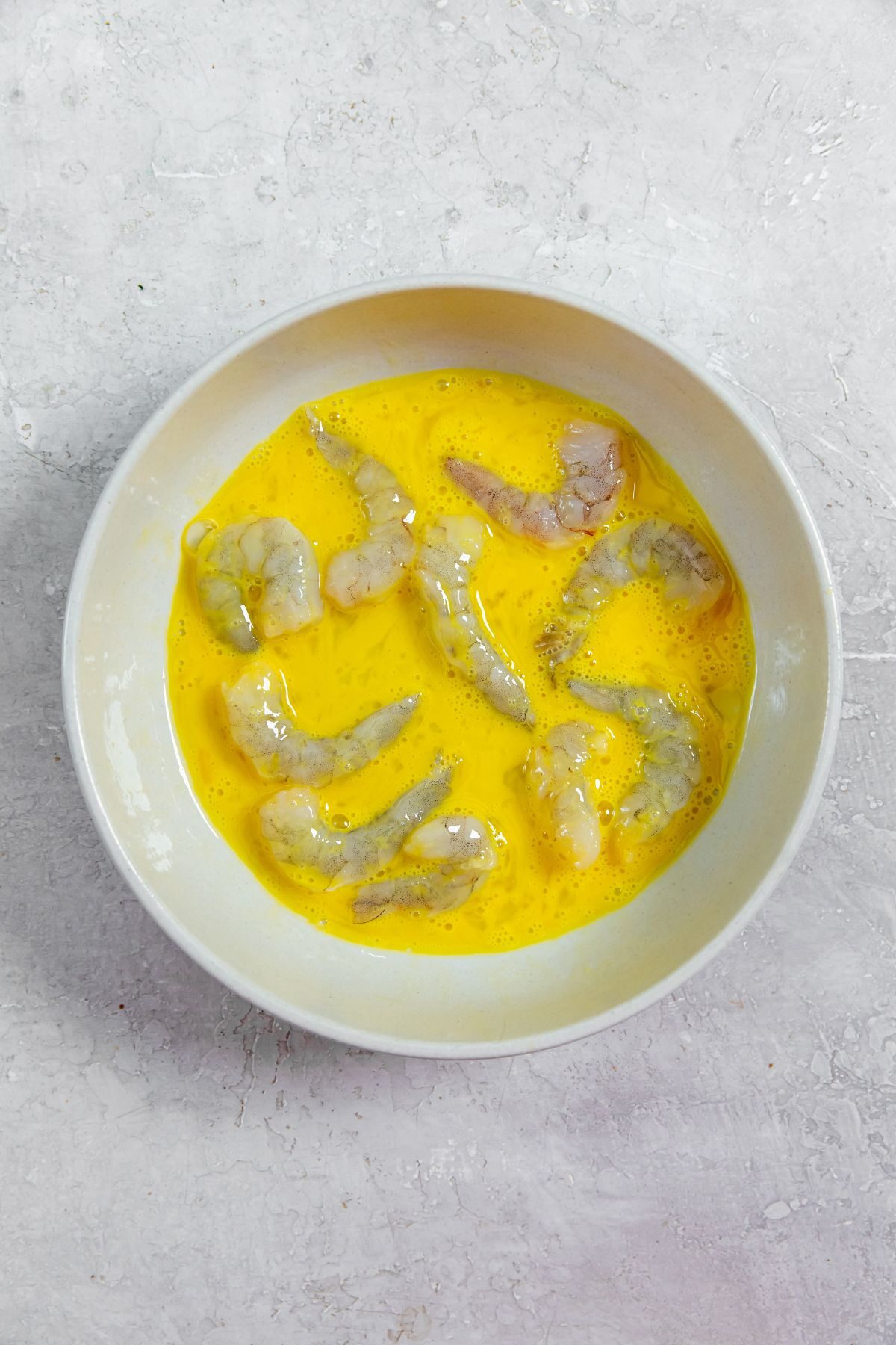 raw shrimp in a bowl with egg mixture