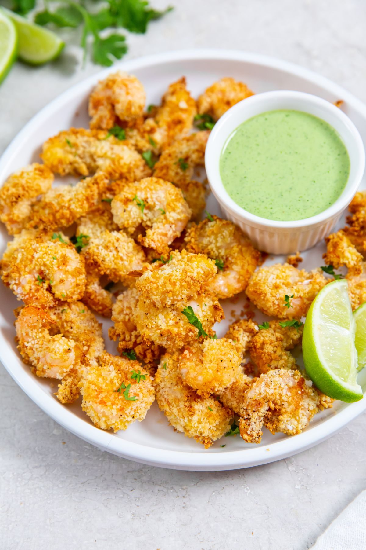 air fried panko shrimp on a white plate with a lime and dipping sauce