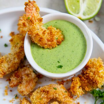 Air Fryer panko shrimp on a white plate dipped in green sauce