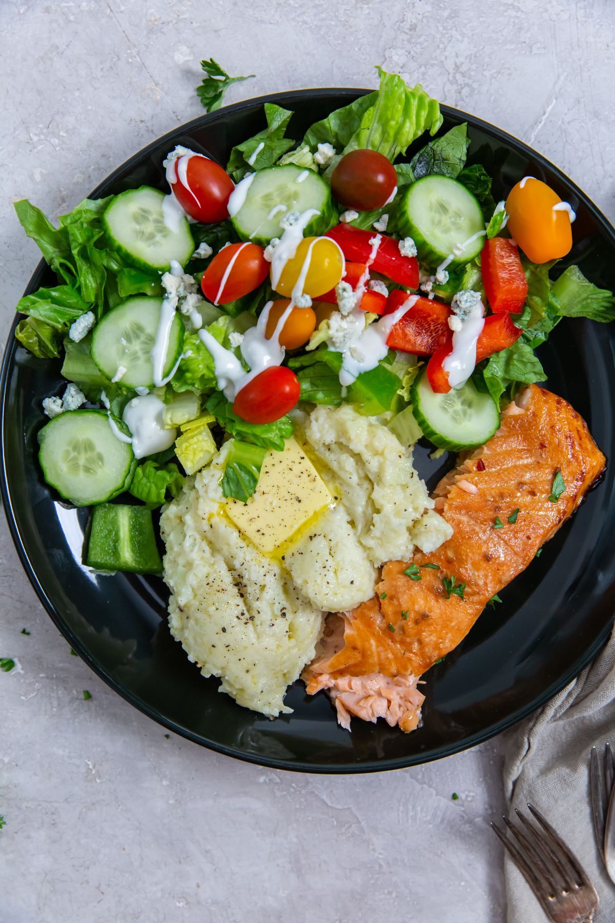air fryer teriyaki salmon with a side salad on a black plate