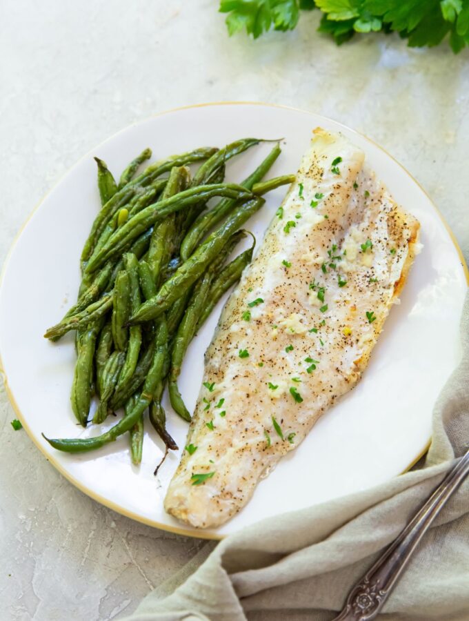 broiled walleye on a white plate with a side of green beans