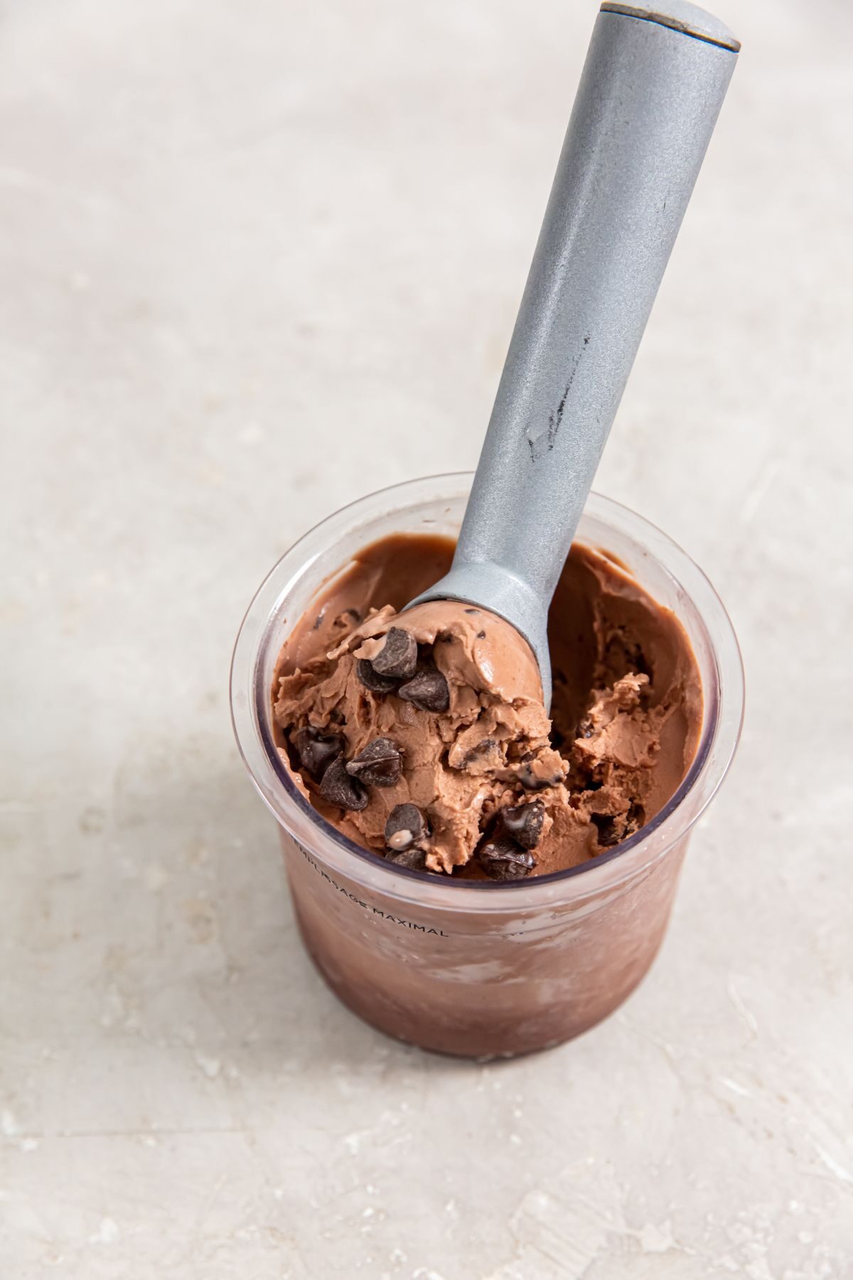 chocolate chocolate chip ice cream in a pint container with an ice cream scoop