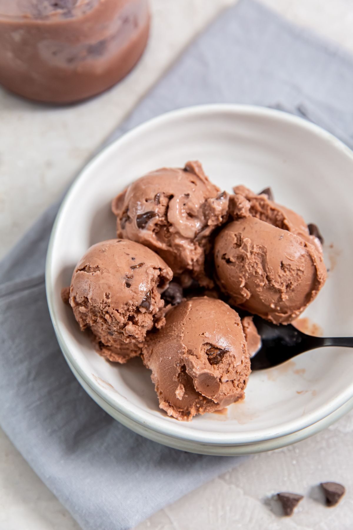 chocolate chocolate chip ice cream in a bowl with a black spoon on top of a light blue napkin