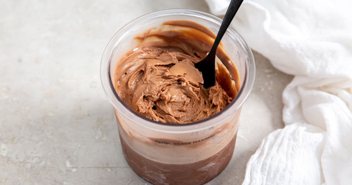 Chocolate protein ice cream in pint container next to white napkin