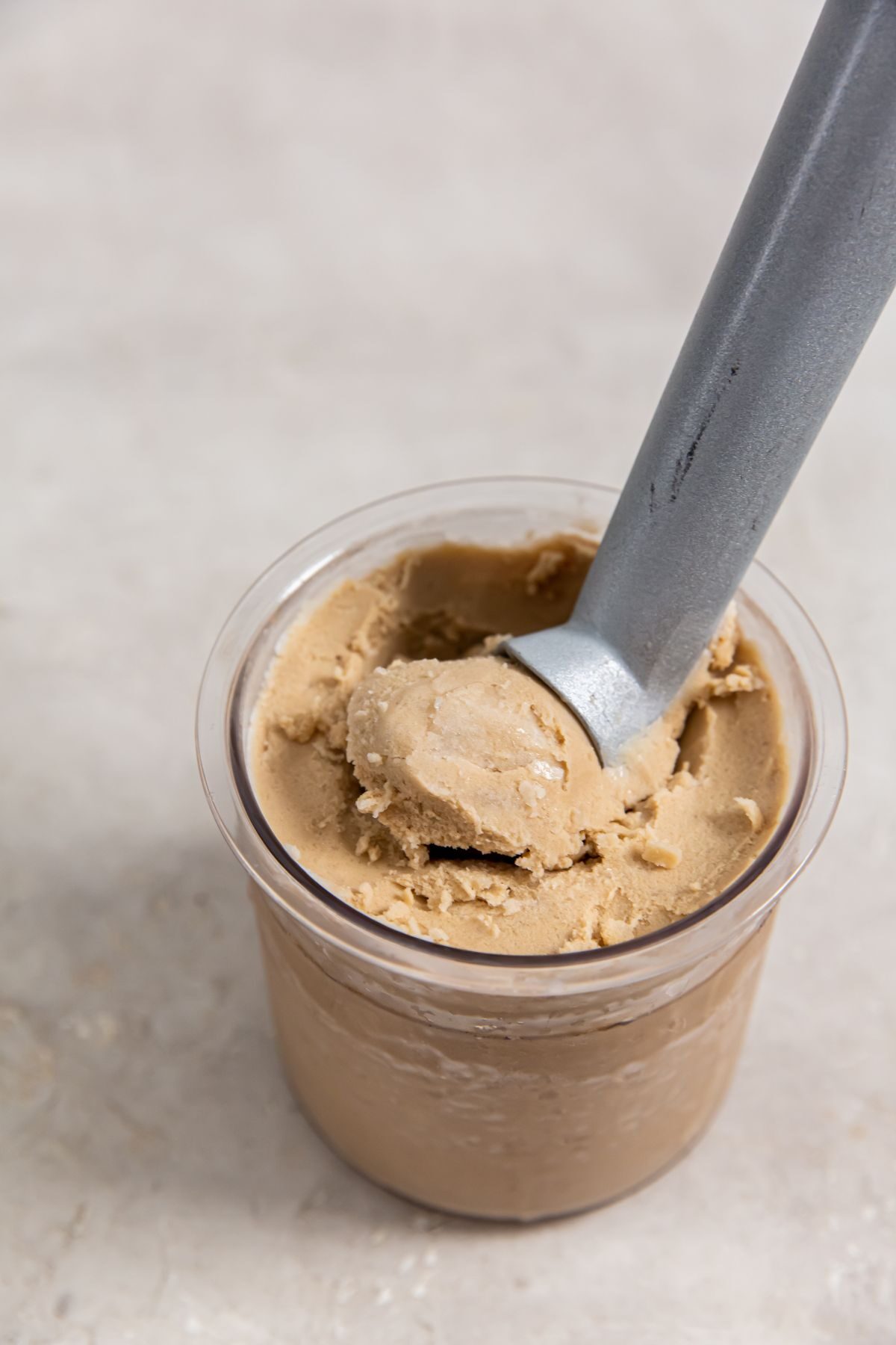 coffee ice cream in a pint container with an ice cream scoop