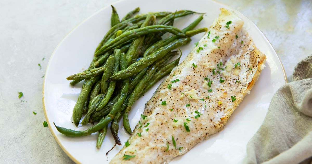 broiled walleye on a white plate with a side of green beans