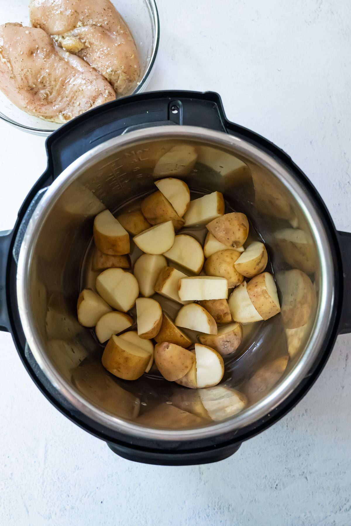Raw quartered potatoes setting inside an instant pot.