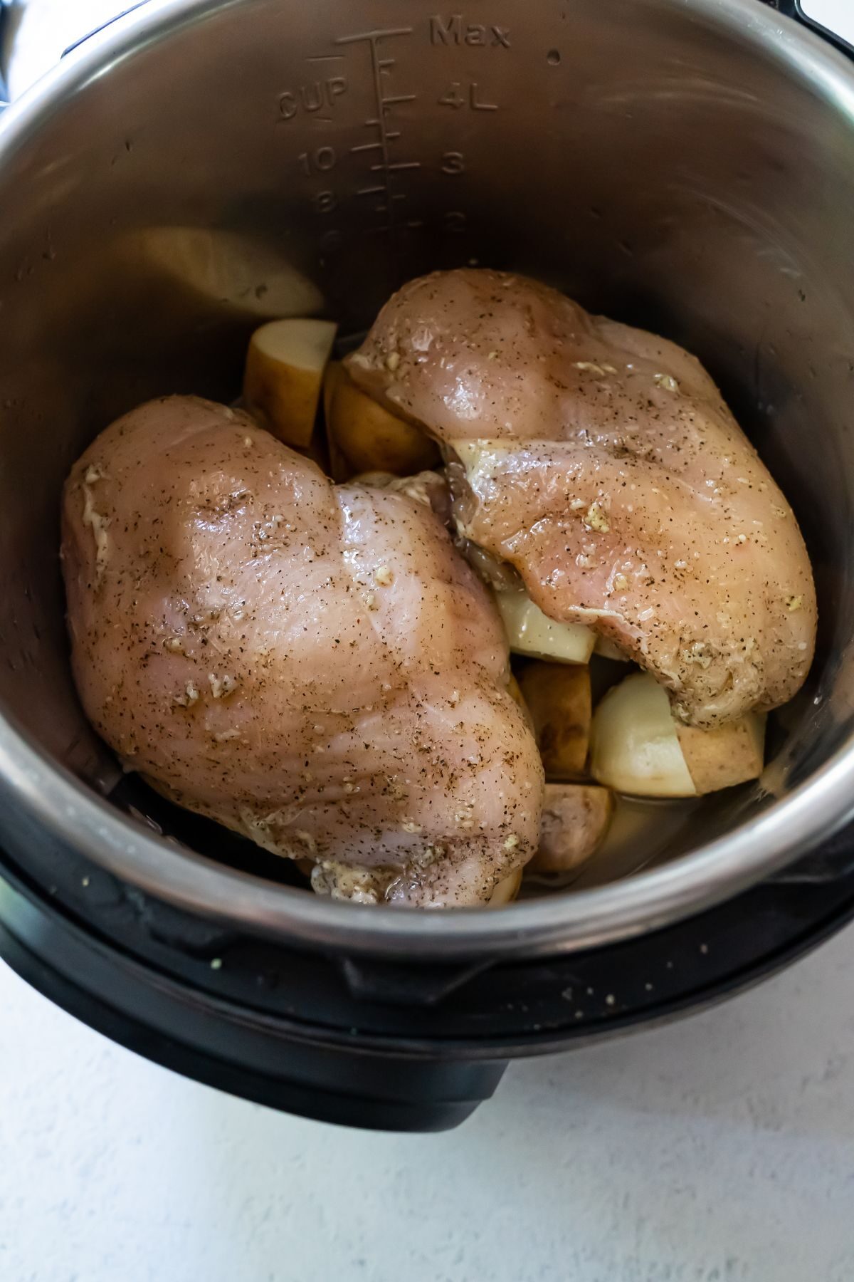 Two chicken breasts and potatoes cooking in an instant pot.