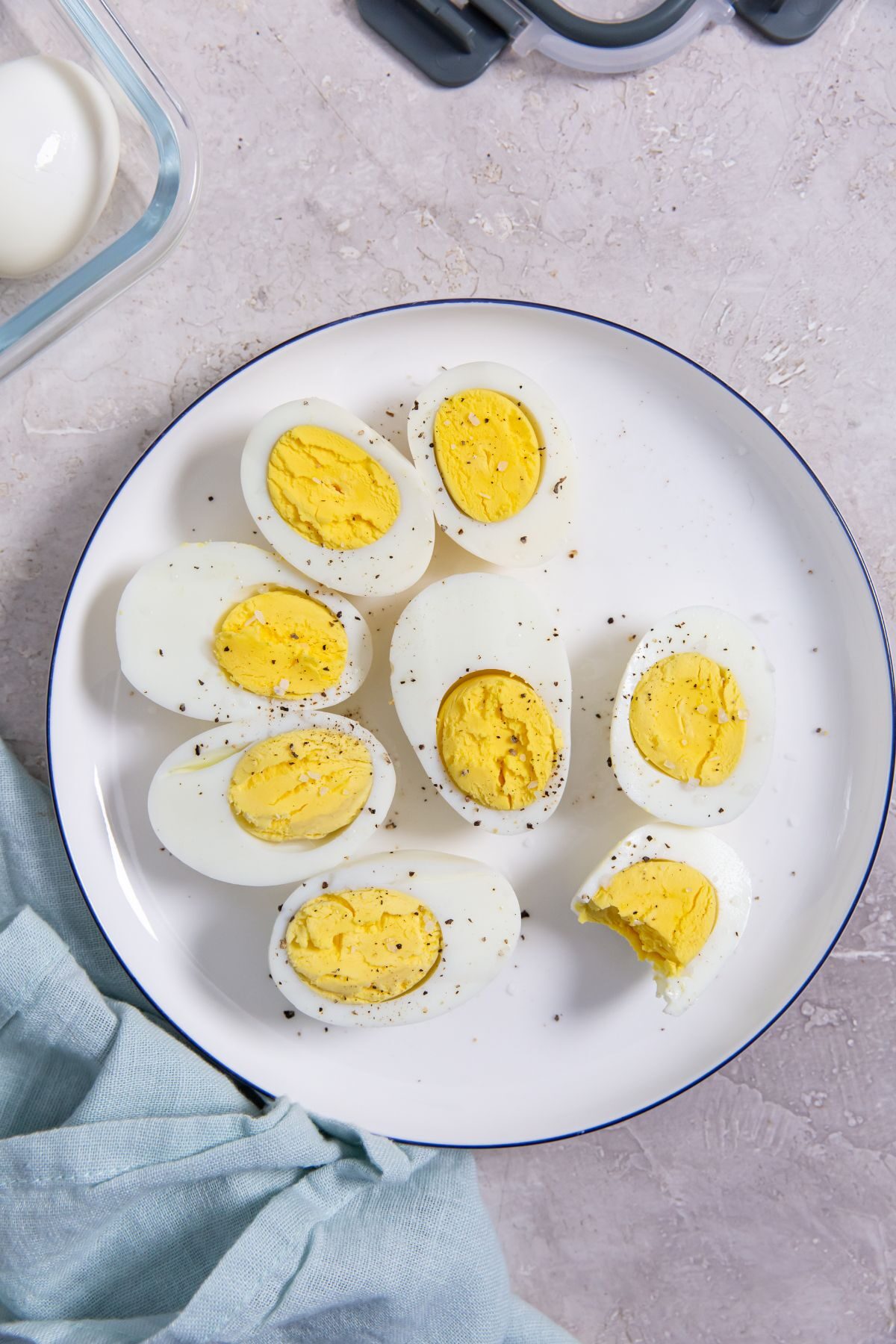 Instant Pot Eggs 5-5-5 Method cut in half on a white plate with a light blue napkin on the side