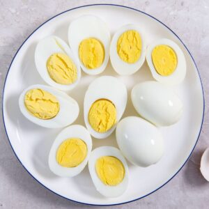 hard boiled eggs sliced in half on a white plate.
