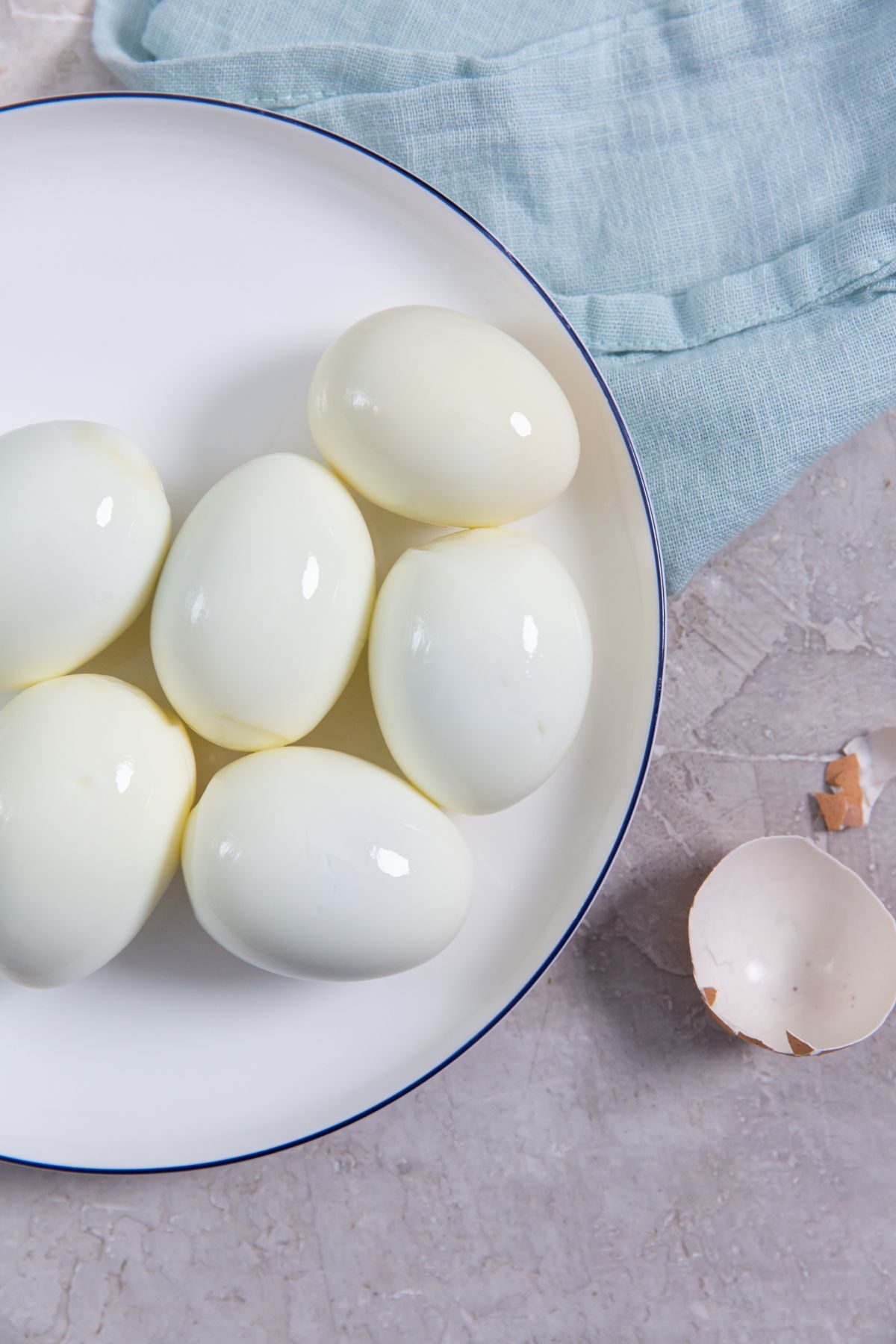 Instant Pot Eggs 5-5-5 Method on a white plate with a light blue napkin and shells on the side