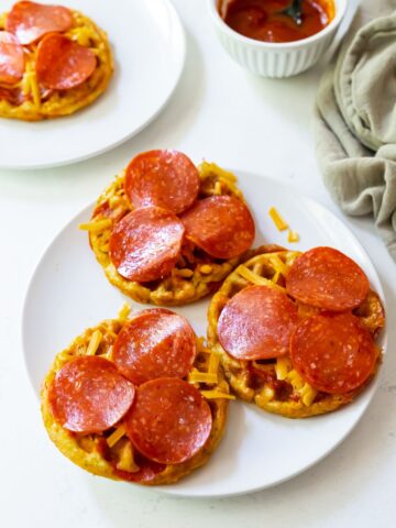 Three pizza chaffles on a white plate.