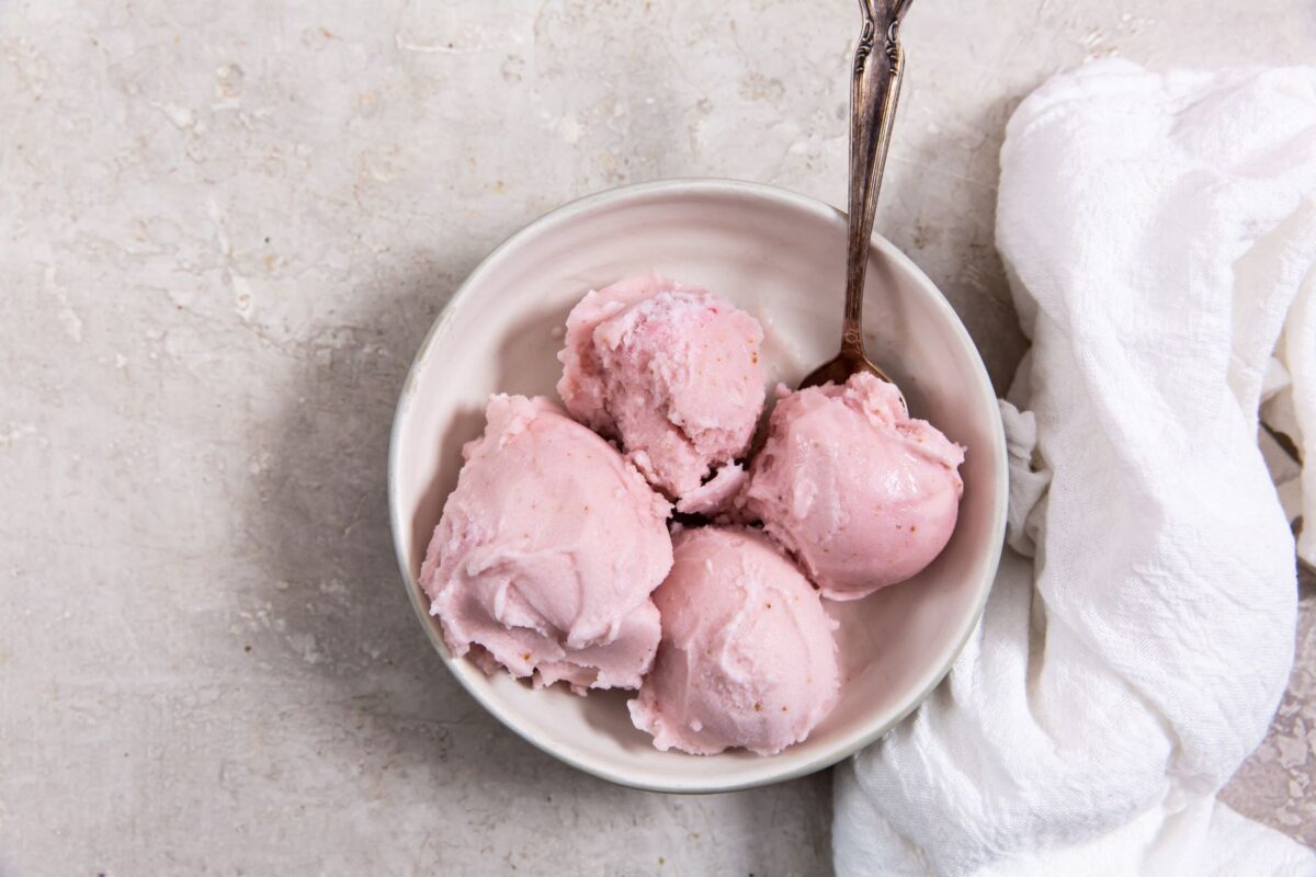 keto strawberry ice cream in a white bowl with a spoon next to a white napkin