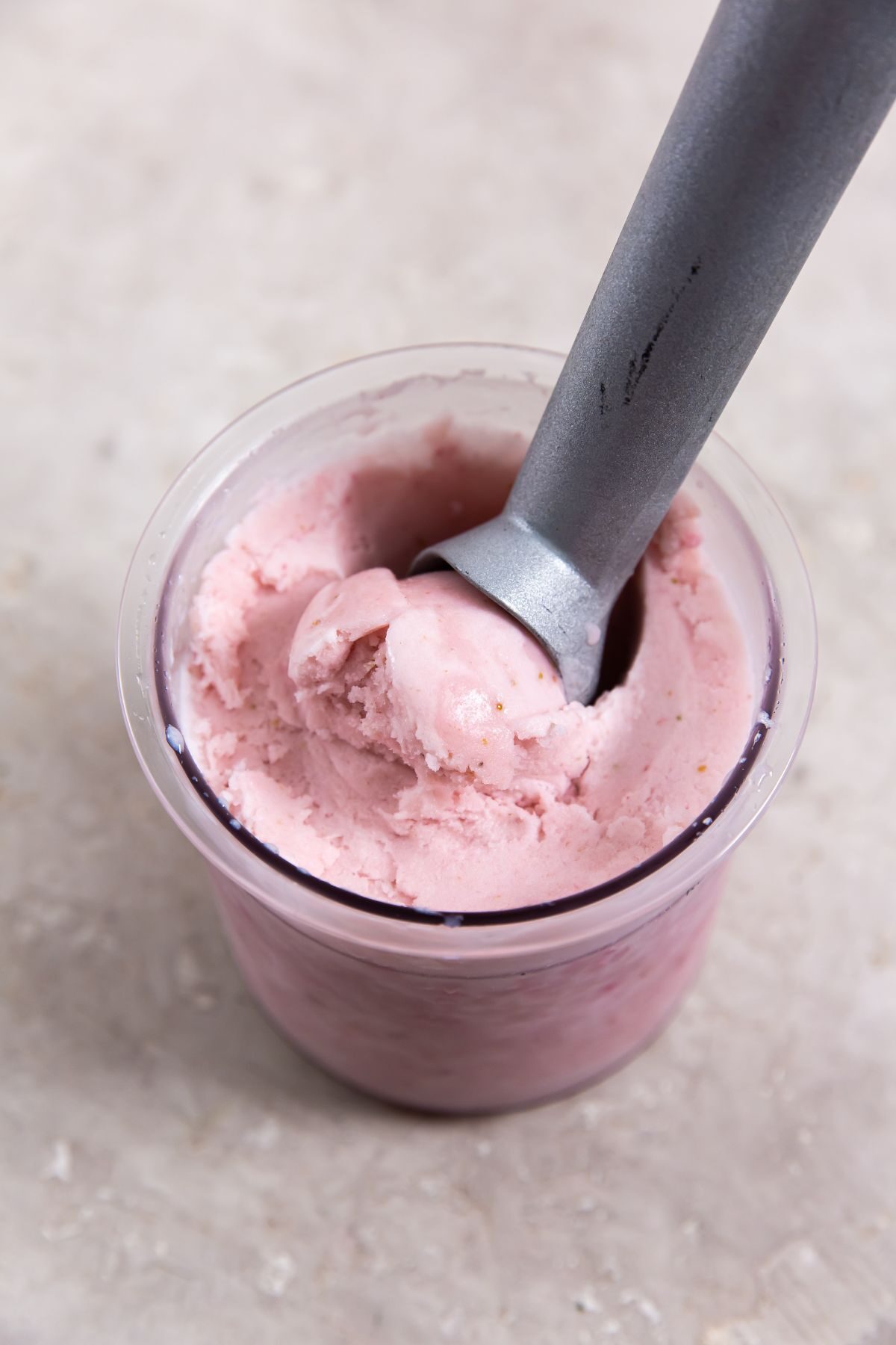 keto strawberry ice cream in a pint jar with an ice cream scoop