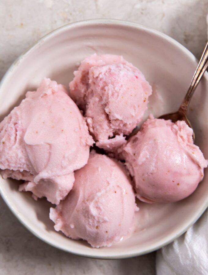 low carb strawberry ice cream in a white bowl with a spoon