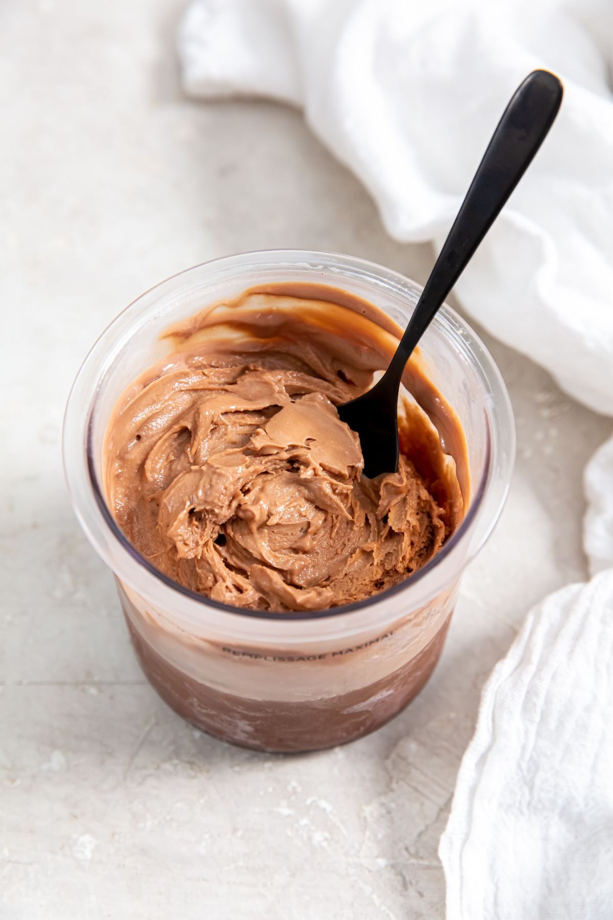Chocolate protein ice cream in pint cup with a spoon
