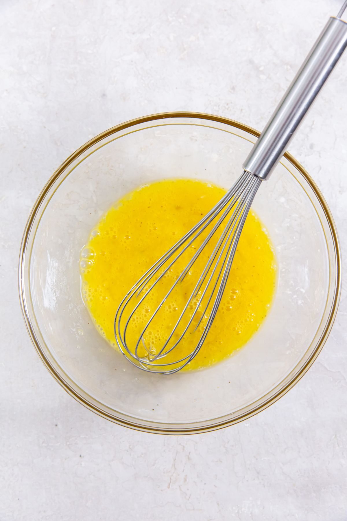 mixed eggs with a whisk in a clear bowl