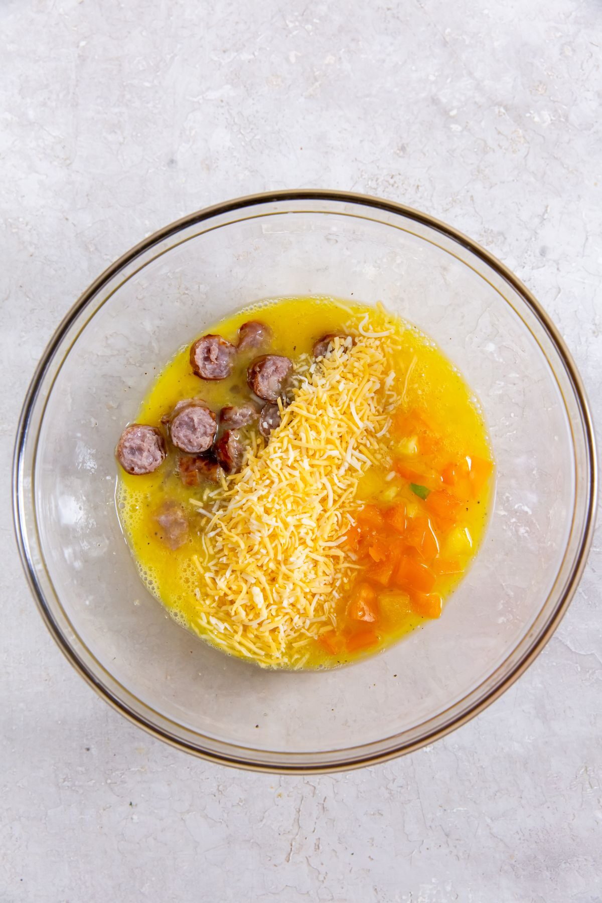 mixed eggs with sausage, cheese and bell peppers in a clear bowl