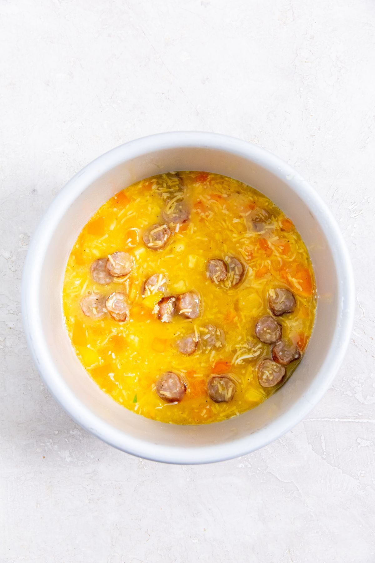 mixed eggs with sausage, cheese and bell peppers in a baking pan