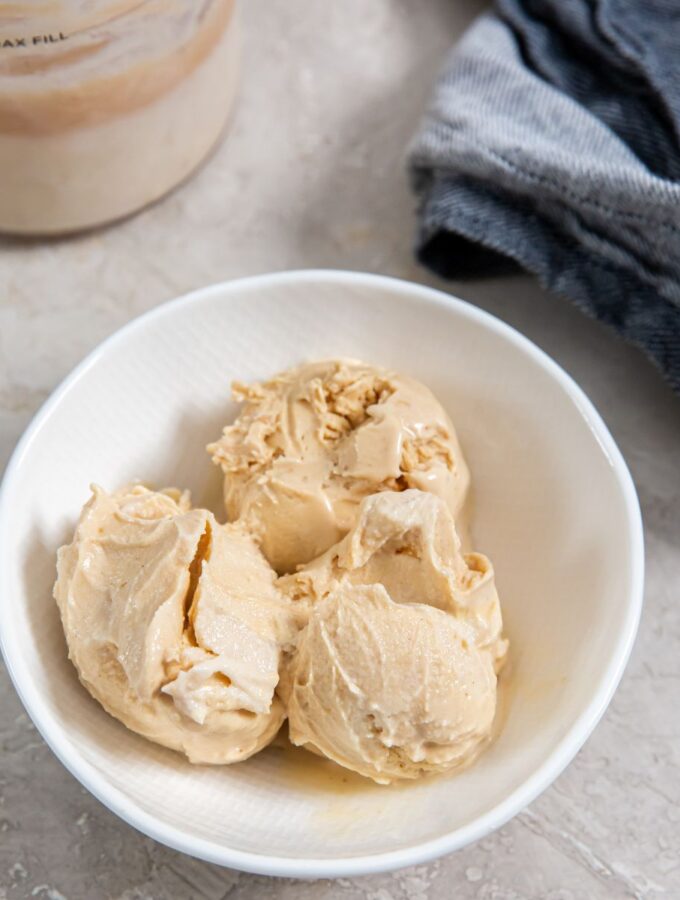 peanut butter ice cream in a white bowl next to a blue napkin
