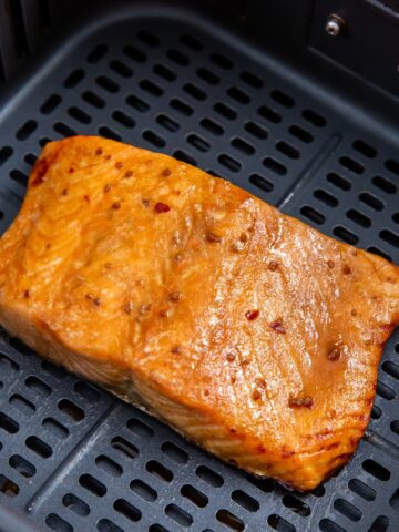 cooked teriyaki salmon in an air fryer basket.