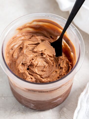 chocolate protein ice cream without bananas in a clear pint and a black spoon and white napkin