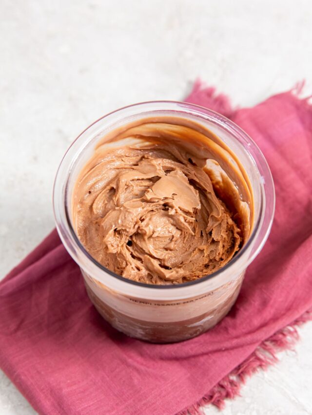 Chocolate protein ice cream in clear container on pink towel