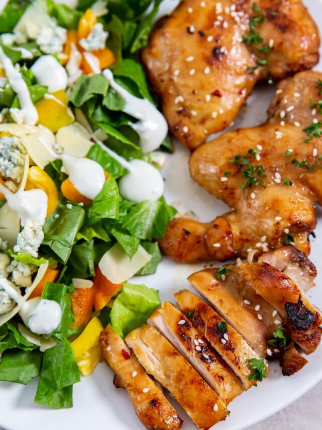Air Fryer Teriyaki Chicken Thighs on a white plate with a salad on the side