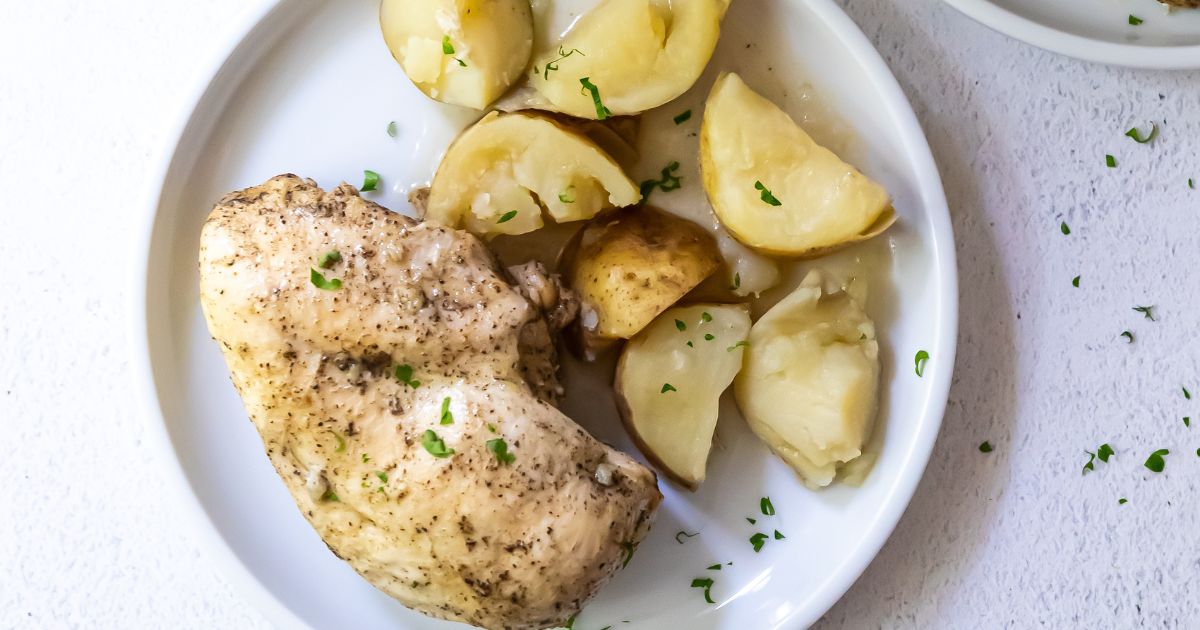 cooked chicken and potatoes on a white plate topped with parsley