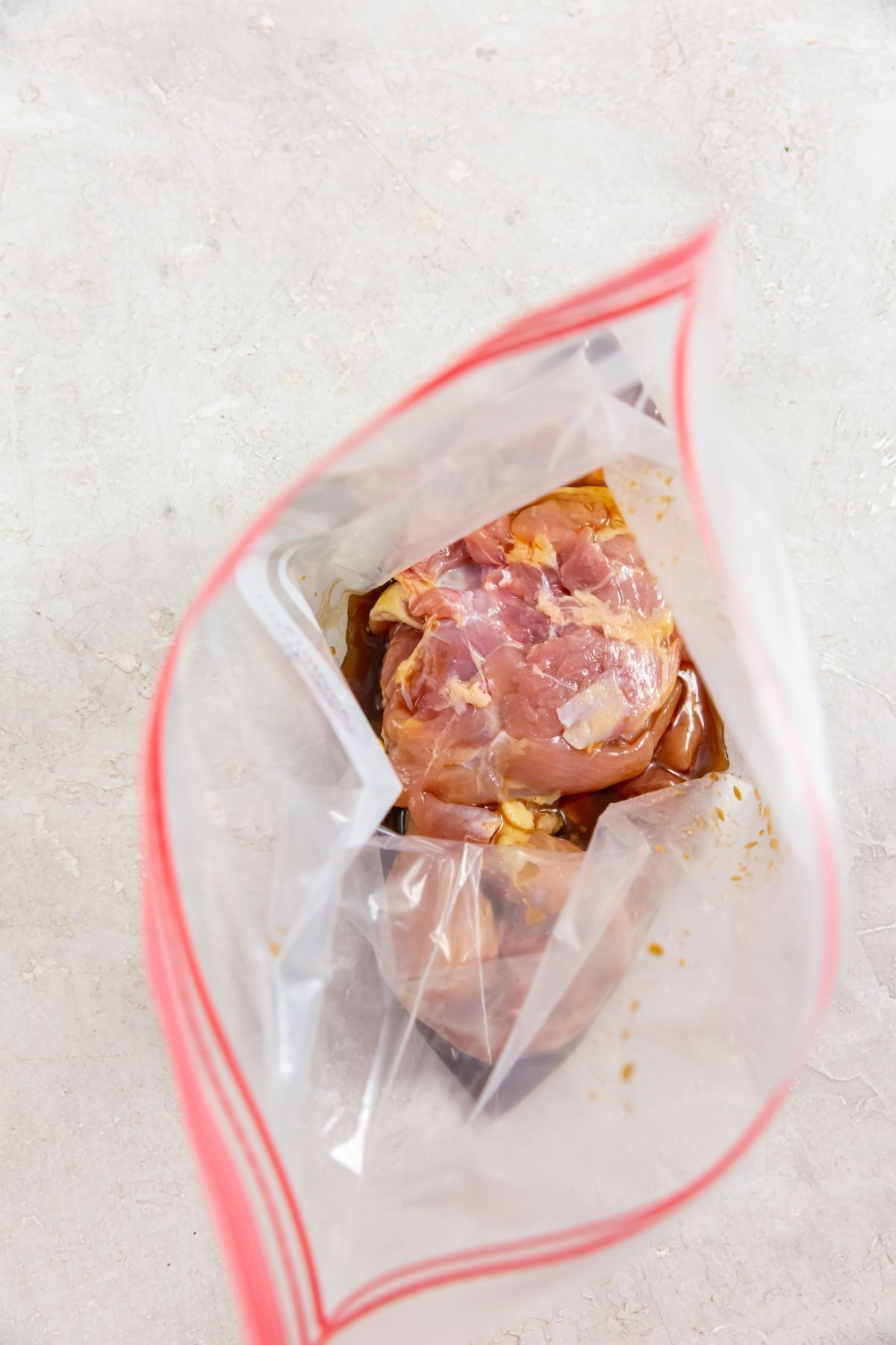 ingredients of raw chicken thighs and paleo teriyaki sauce in a baggie