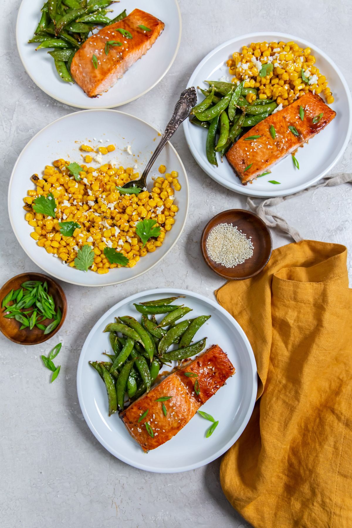 Air Fryer frozen salmon with teriyaki sauce on a white plate with a side of snap peas and a side of corn