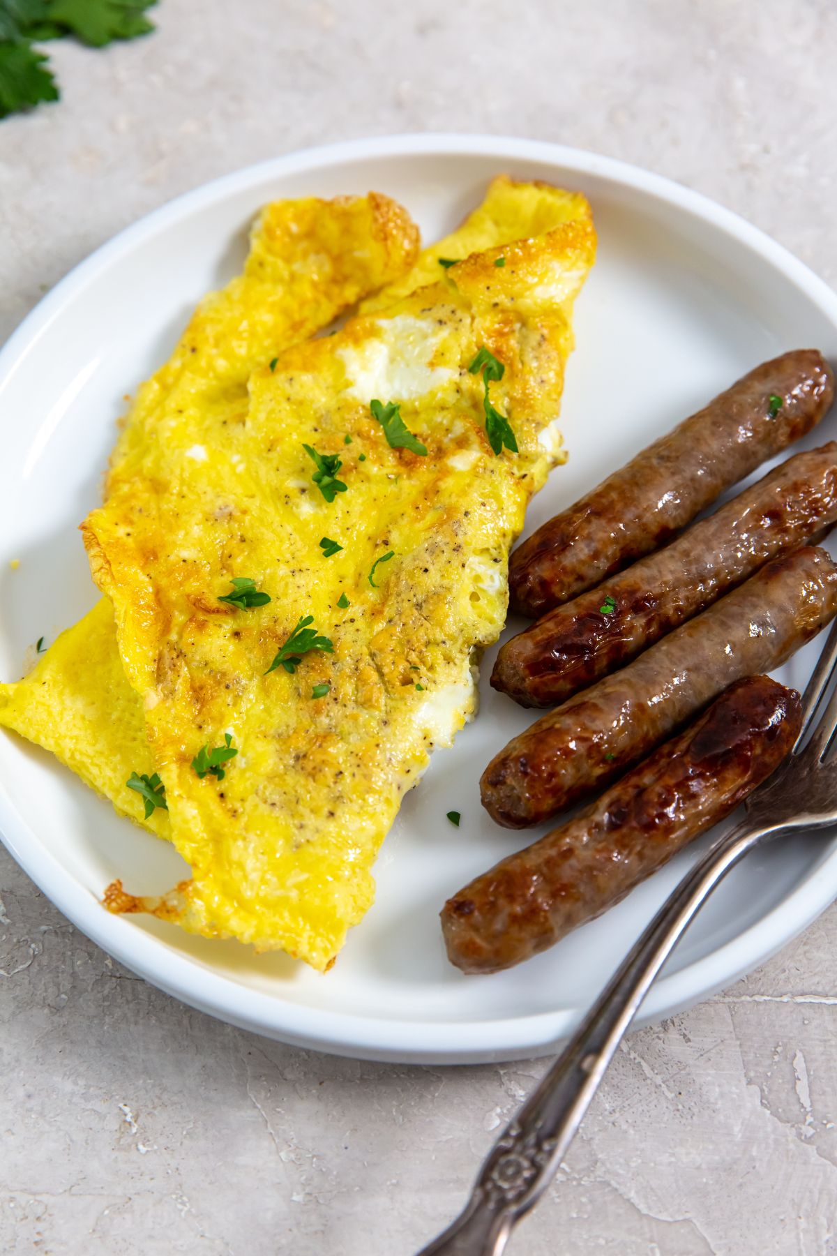 air fryer scrambled eggs with a side of breakfast sausage with a fork
