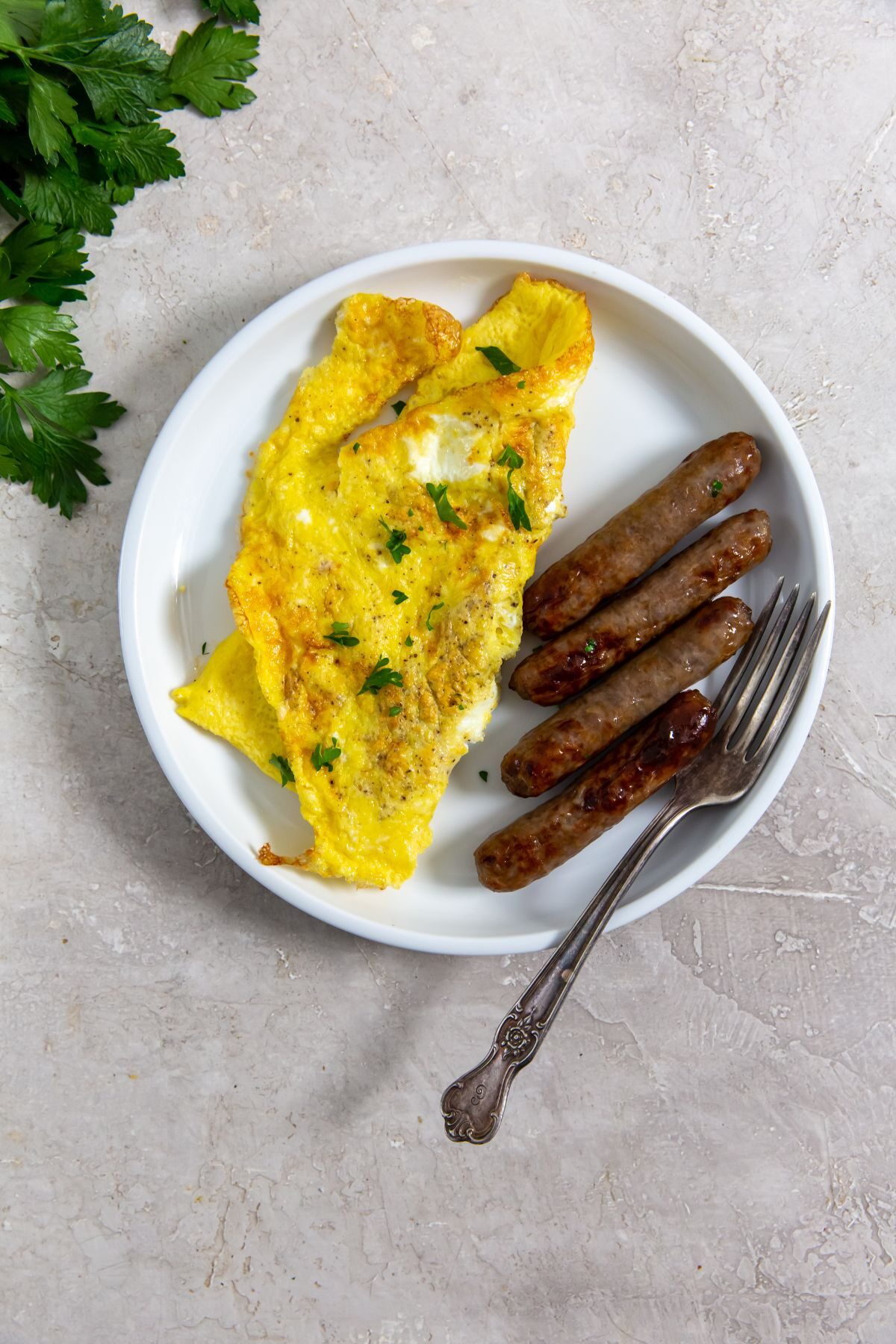air fryer scrambled eggs with a side of breakfast sausage with a fork