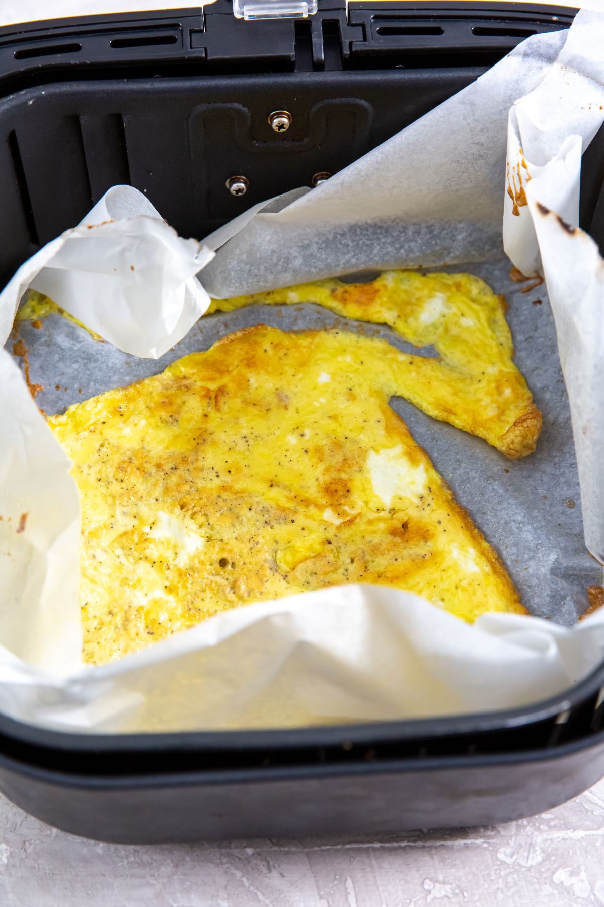 parchment paper in the air fryer with cooked scrambled eggs