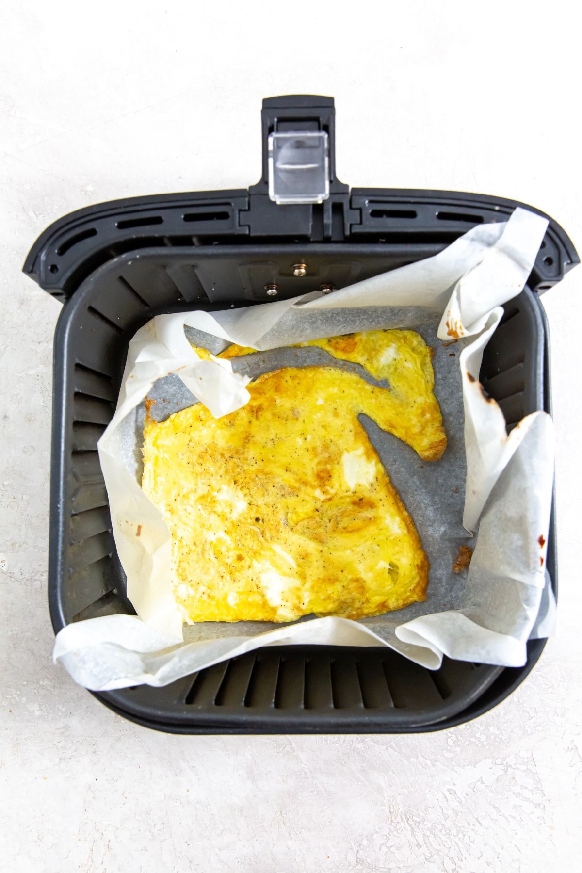 parchment paper in the air fryer with cooked scrambled eggs
