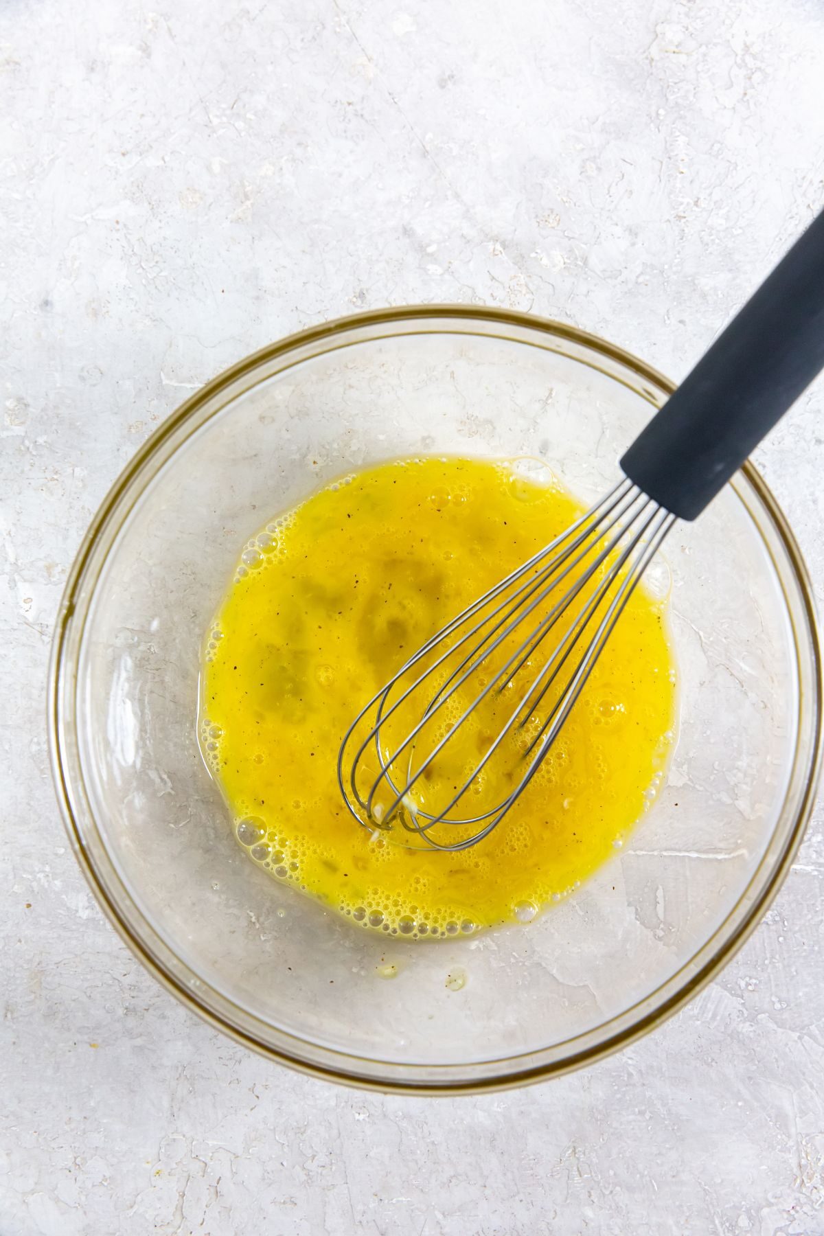 egg mixture with a whisk in a clear bowl