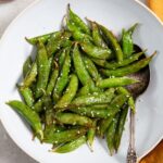 Air Fryer Sugar Snapped Peas on a white plate with an orange napkin
