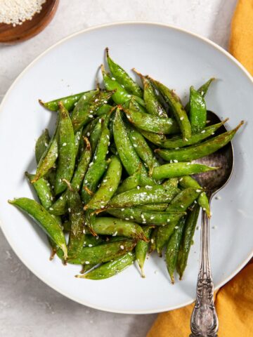 Air Fryer Sugar Snapped Peas on a white plate with an orange napkin