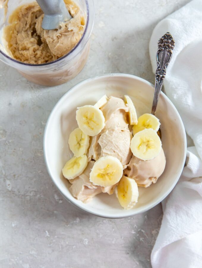 Ninja Creami Banana Ice Cream in a white bowl with sliced bananas on top