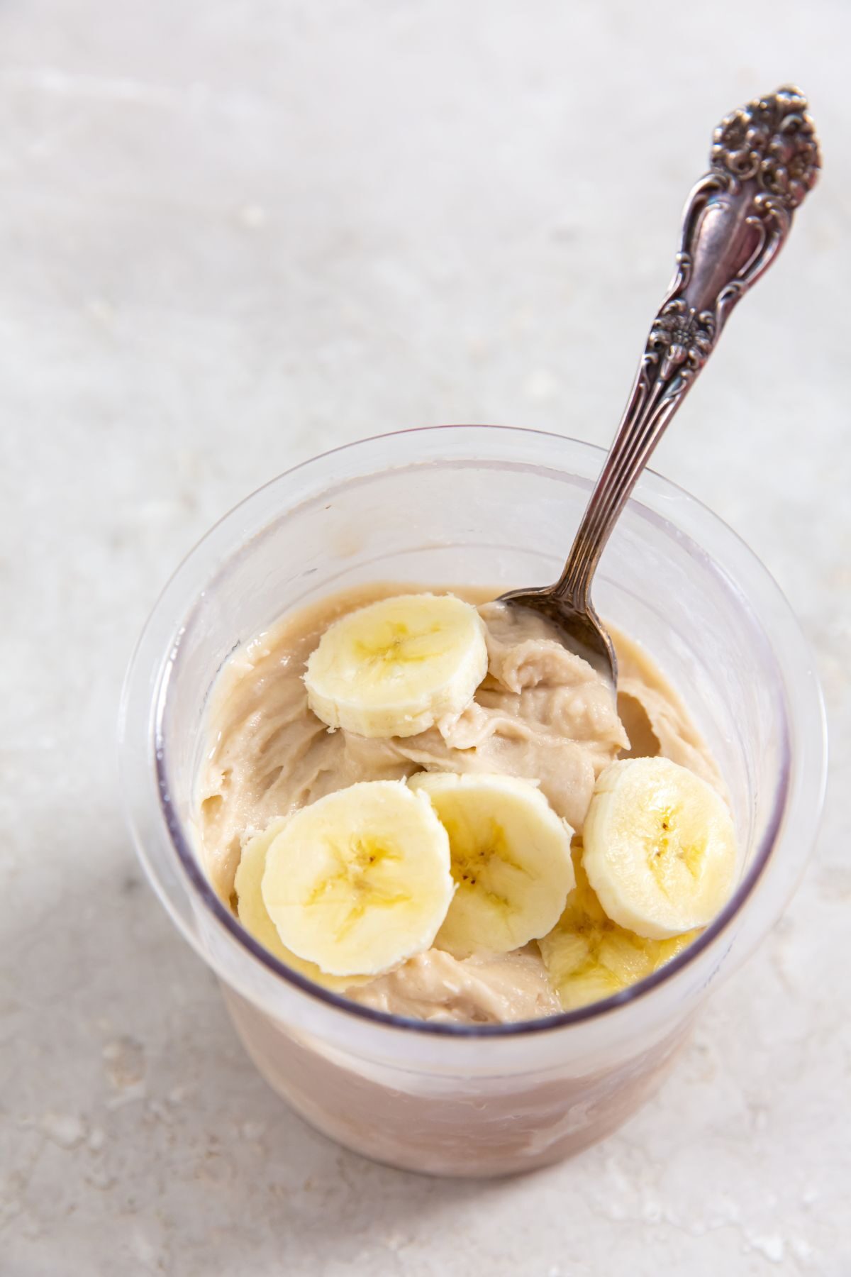 Ninja Creami Banana Ice Cream in a pint with sliced bananas on top and a spoon in it