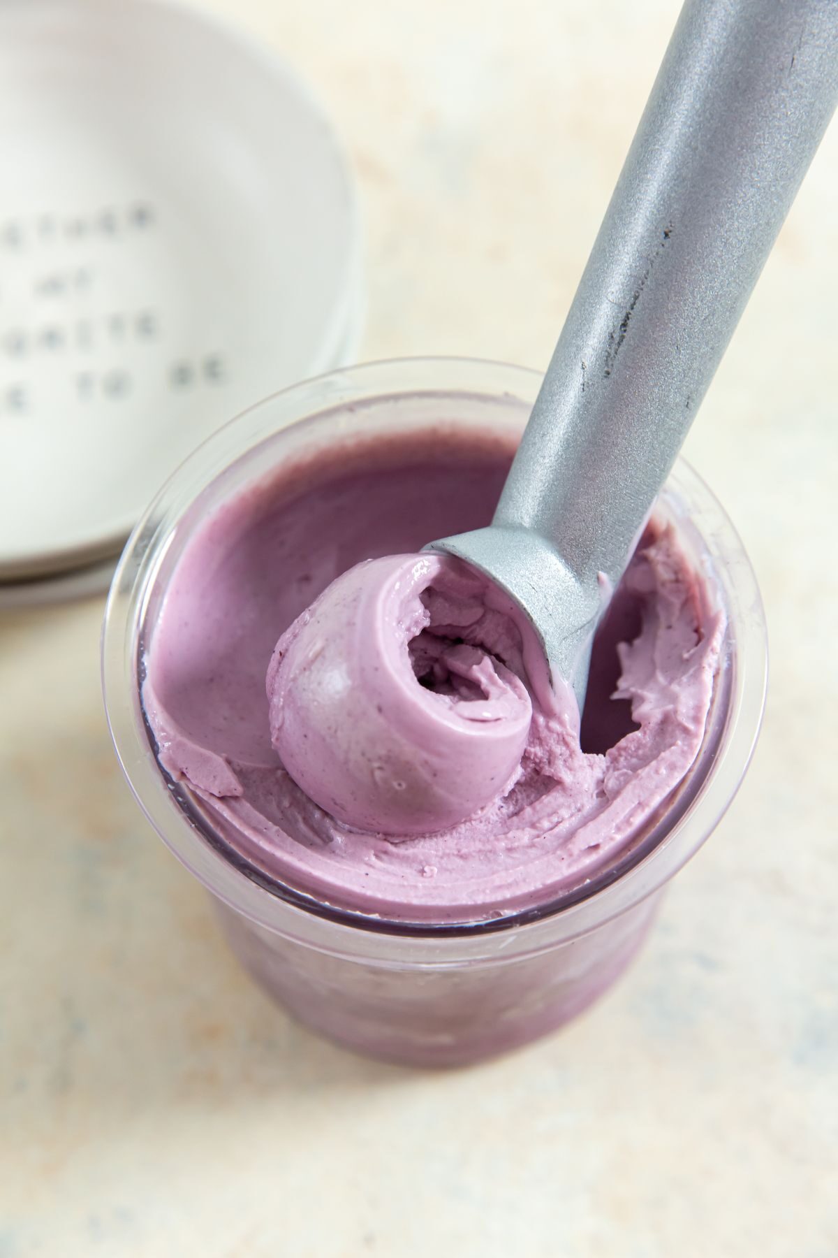 ninja creami low carb blueberry frozen yogurt in a pint with an ice cream scoop in it