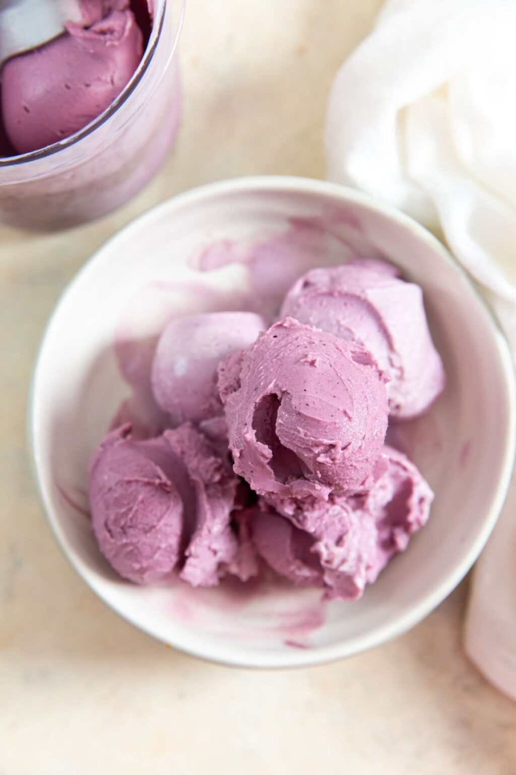 Bluberry Frozen Yogurt in a white bowl with an ice cream scoop.