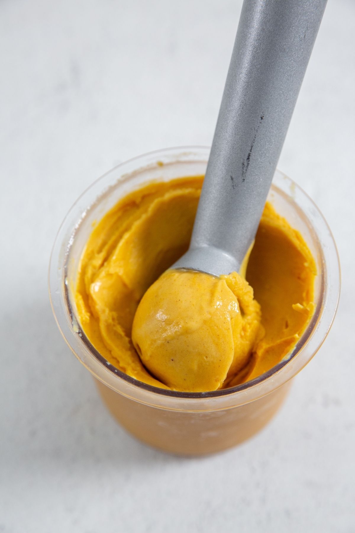 Ninja Creami Pumpkin Ice Cream in the ninja creami container with an ice cream spoon and white napkin