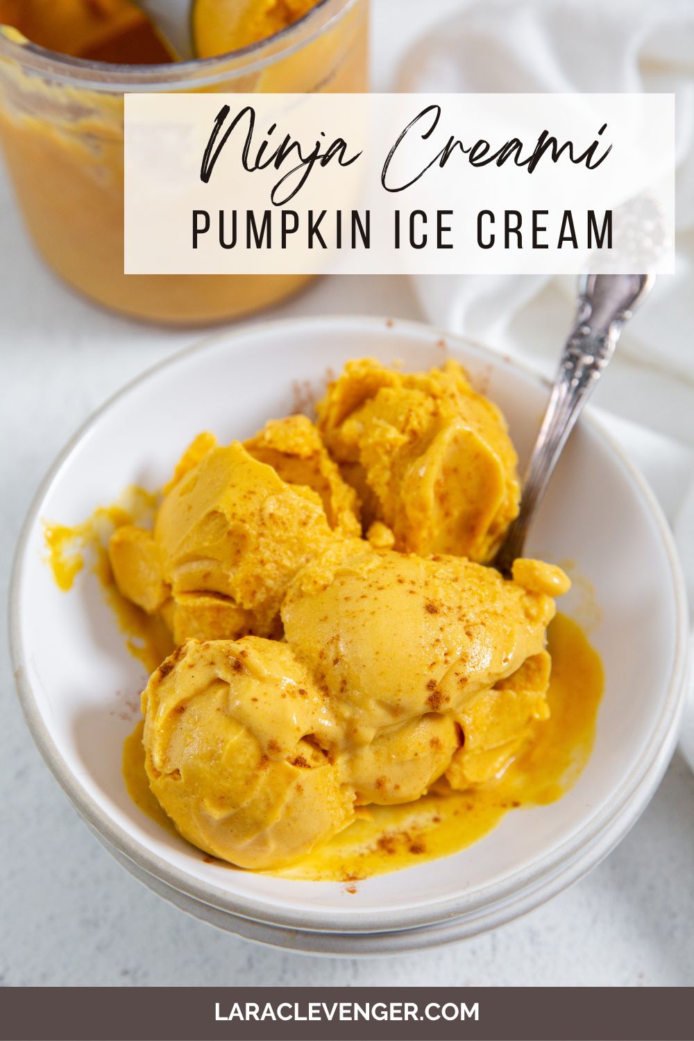 pin of Ninja Creami Pumpkin Ice Cream in a bowl with a spoon in it and a white napkin on the side