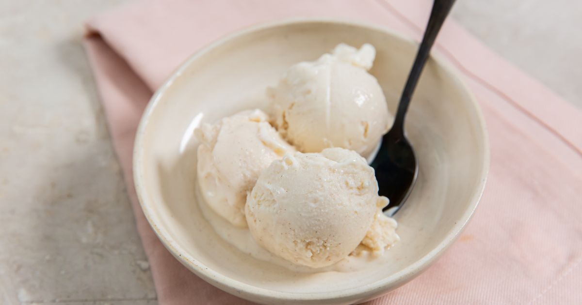 Snickerdoodle ice cream in a white bowl with a spoon and pink napkin on the side.